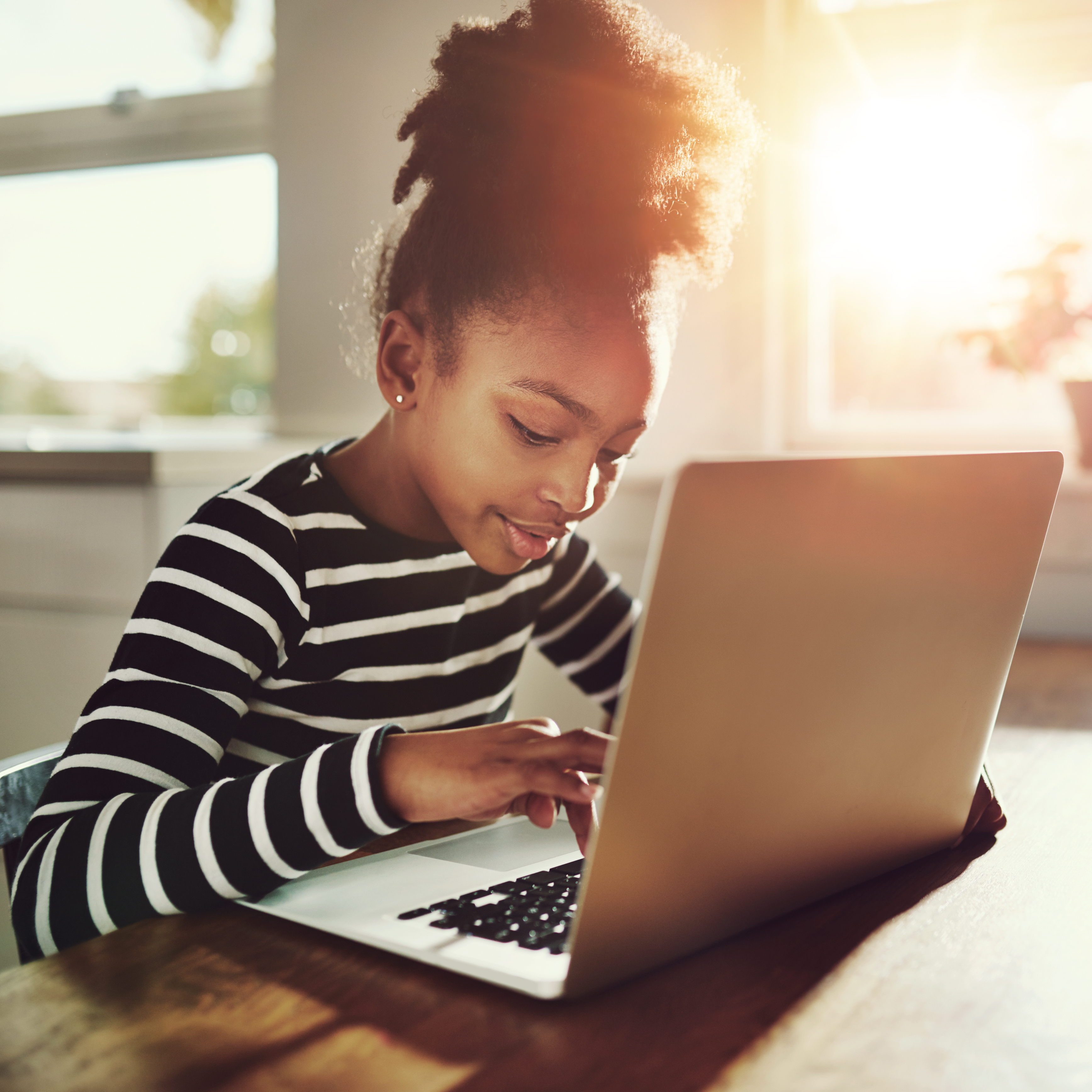Learning on Laptop A Black kid with natural hair in a puffy updo