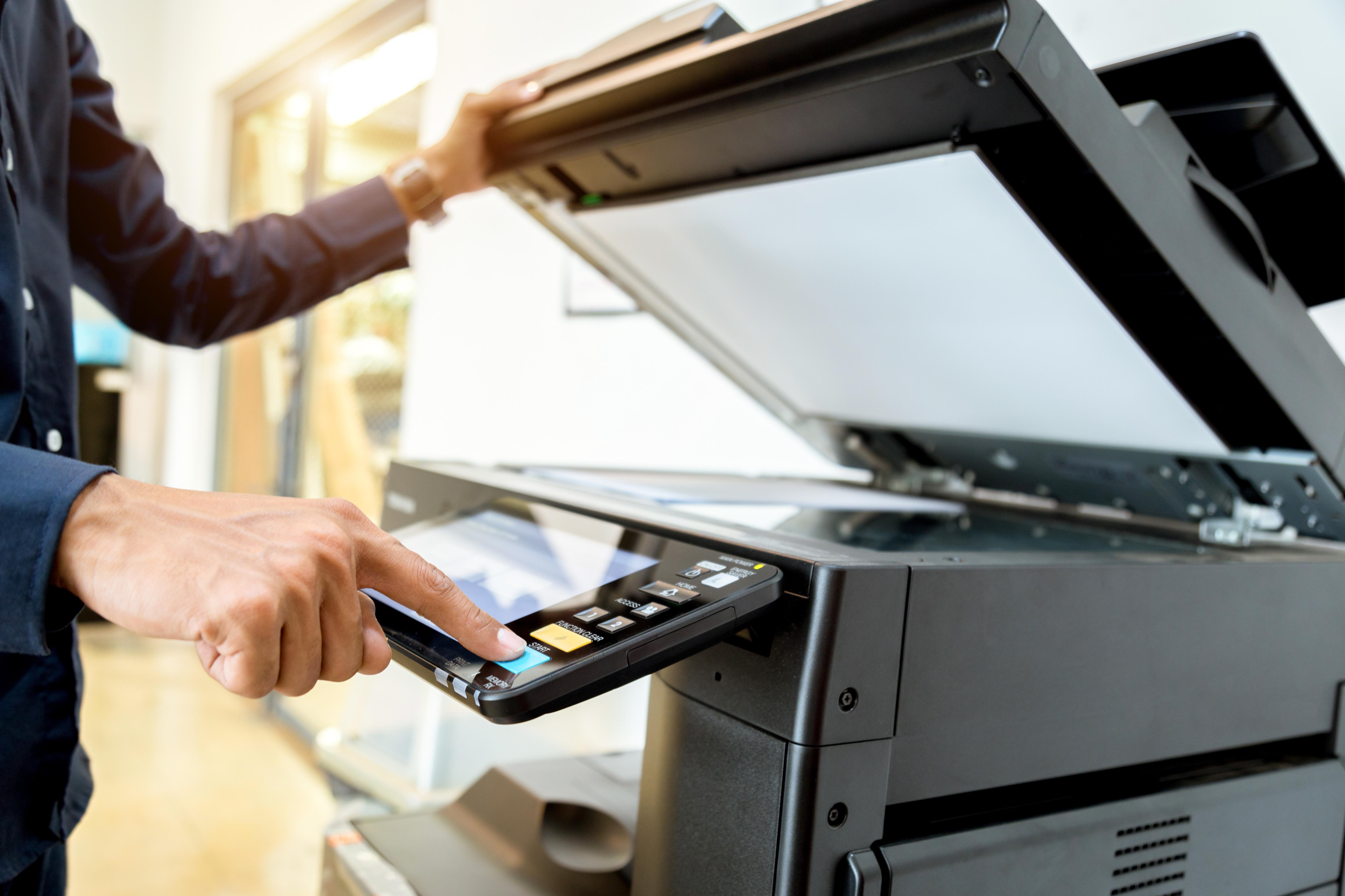A person presses the button on a printer's touch panel and holds the top open to scan a file.
