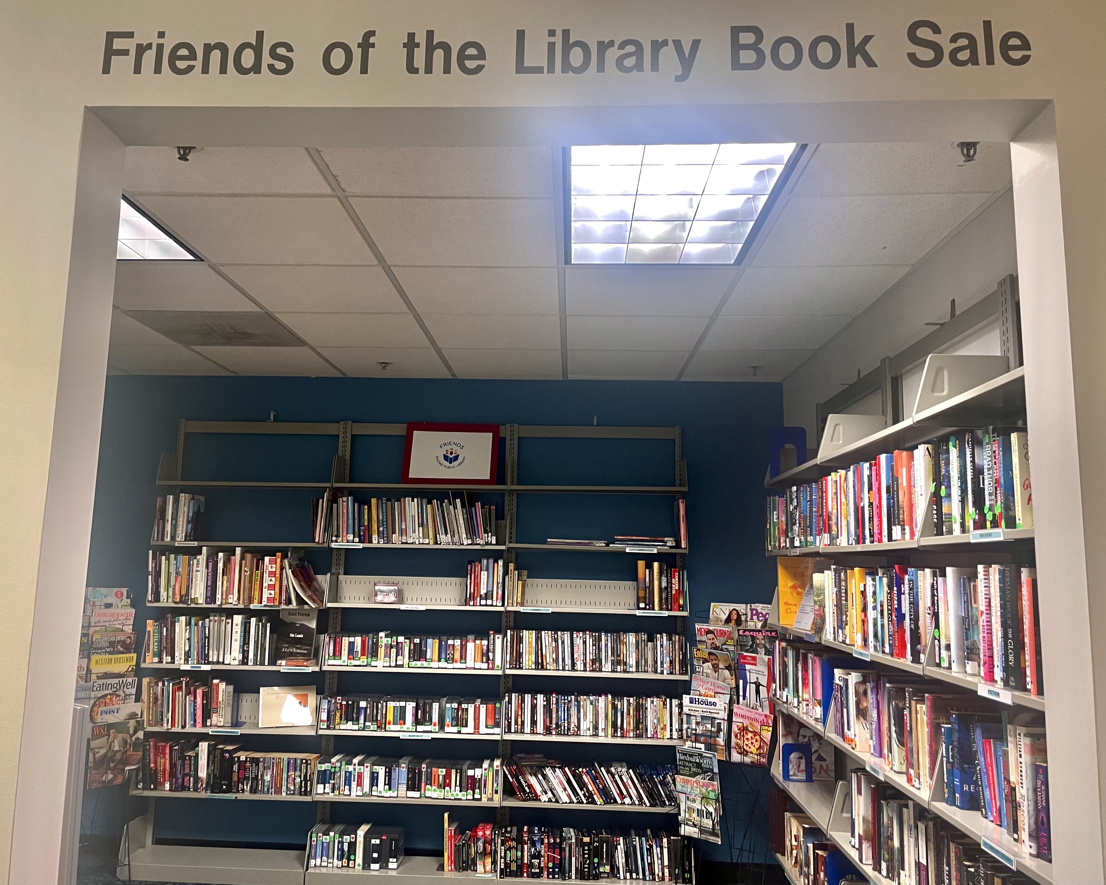 A photo of the Friends of the Library book sale room at the Racine Public Library. It's a cube-shaped, ocean blue room with bookshelves lining its walls.