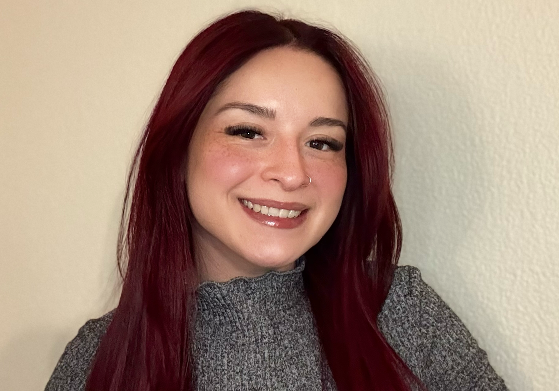 25-12 Ashley Cedeño Headshot - horizontal A photo of a library staff member: Social Worker Ashley Cedeño, a Latinx woman with straight, dark red hair past her shoulders.